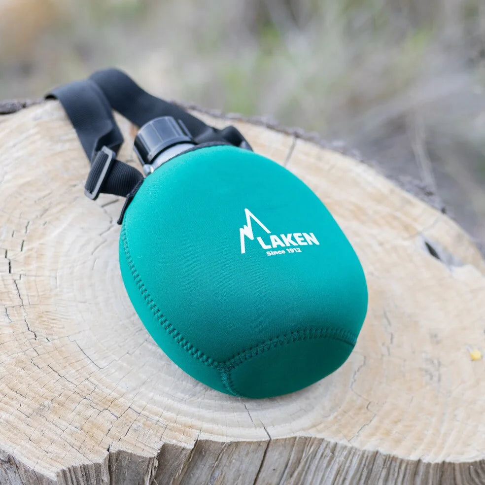 Cantimplora LAKEN de neopreno verde apoyada en un tronco de madera cortado